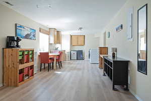 Kitchen with light wood-style floors, washer / clothes dryer, electric panel, light wood finish cabinets, and light countertops