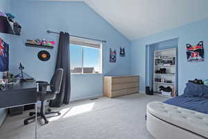 Bedroom with light colored carpet, a desk, and vaulted ceiling