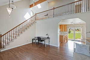 Living room with dark wood finished floors, arched walkways, and a high ceiling