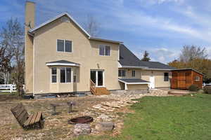 Back of property with entry steps, a patio, a yard, a chimney, and stucco siding