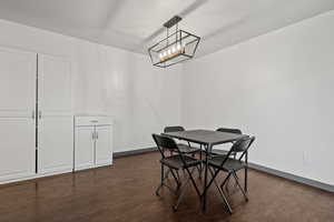Dining space with dark wood-style floors and a chandelier
