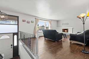 Living area featuring a chandelier, a lit fireplace, and dark wood finished floors