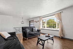 Living room featuring wood finished floors and suspended lighting, with window reading nook