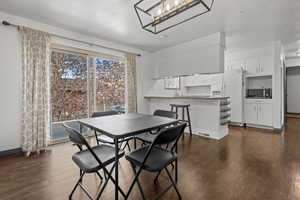 Dining area with dark wood-style floors and a chandelier