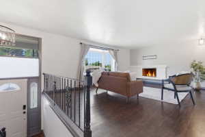 Spacious living area featuring dark wood-finish flooring, a modern fireplace with a white hearth, and large picture windows