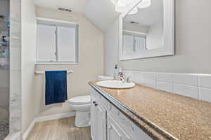 Full basement bathroom with vanity, walk in shower, light wood-style flooring, and healthy amount of natural light