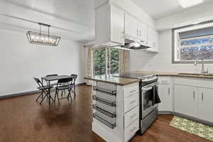 Kitchen featuring stainless steel range with electric cooktop, white cabinets, dark wood-style flooring, backsplash, and a textured ceiling
