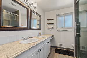 Bathroom featuring a shower stall, double vanity, and light wood finished floors