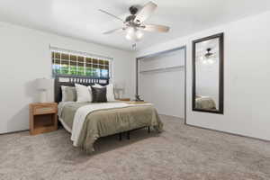 Bedroom featuring light gray carpeting, a window with horizontal blinds, a ceiling fan with integrated lighting, and an open closet space with a clothing rod