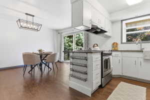 Kitchen and dining area featuring wood-finish flooring, white cabinetry, a stainless steel range, and a sliding glass door