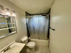 Bathroom featuring vanity, a textured ceiling, and shower / bath combo with shower curtain