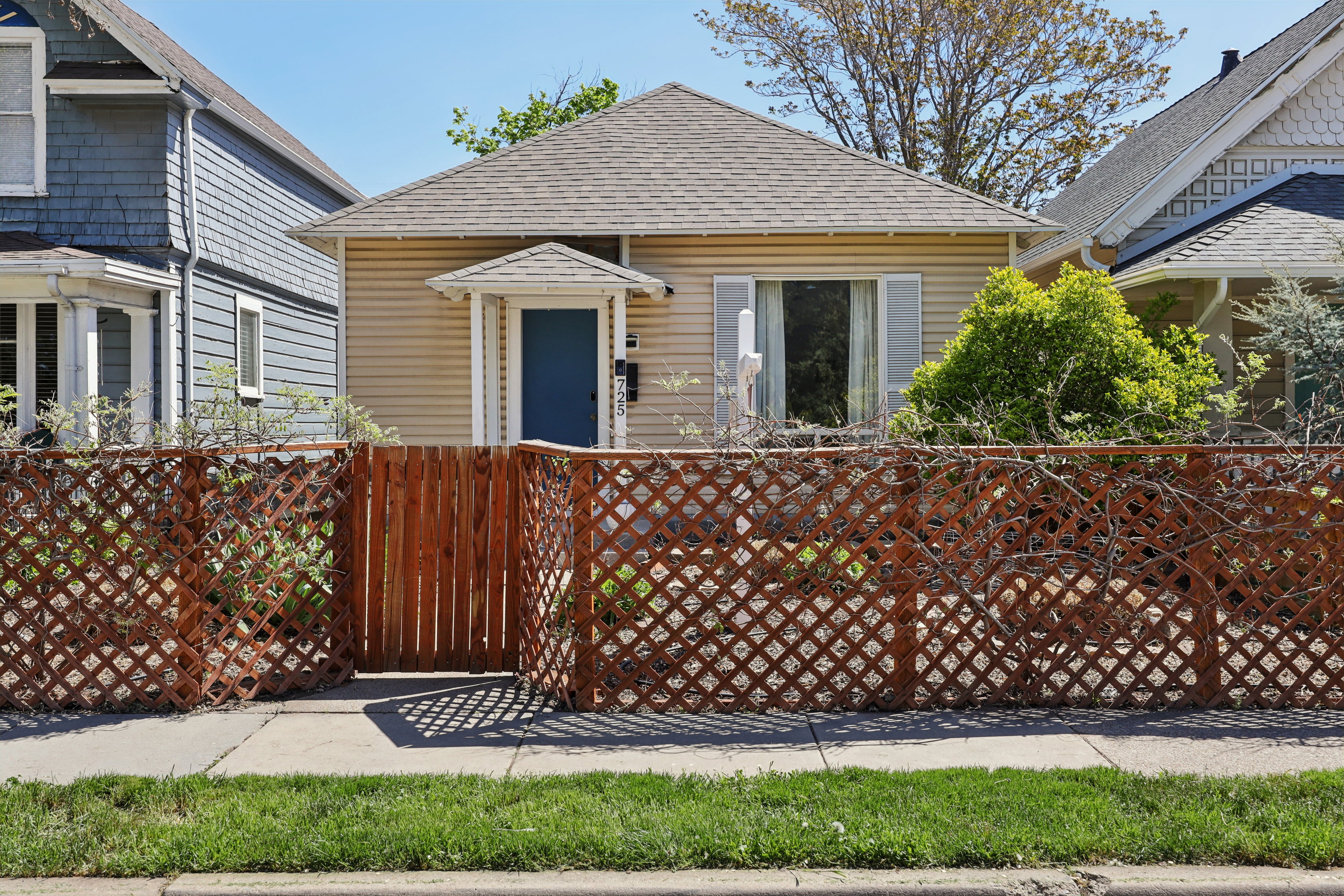 View of front of home with a fenced front yard, roof with shingles, and a gate