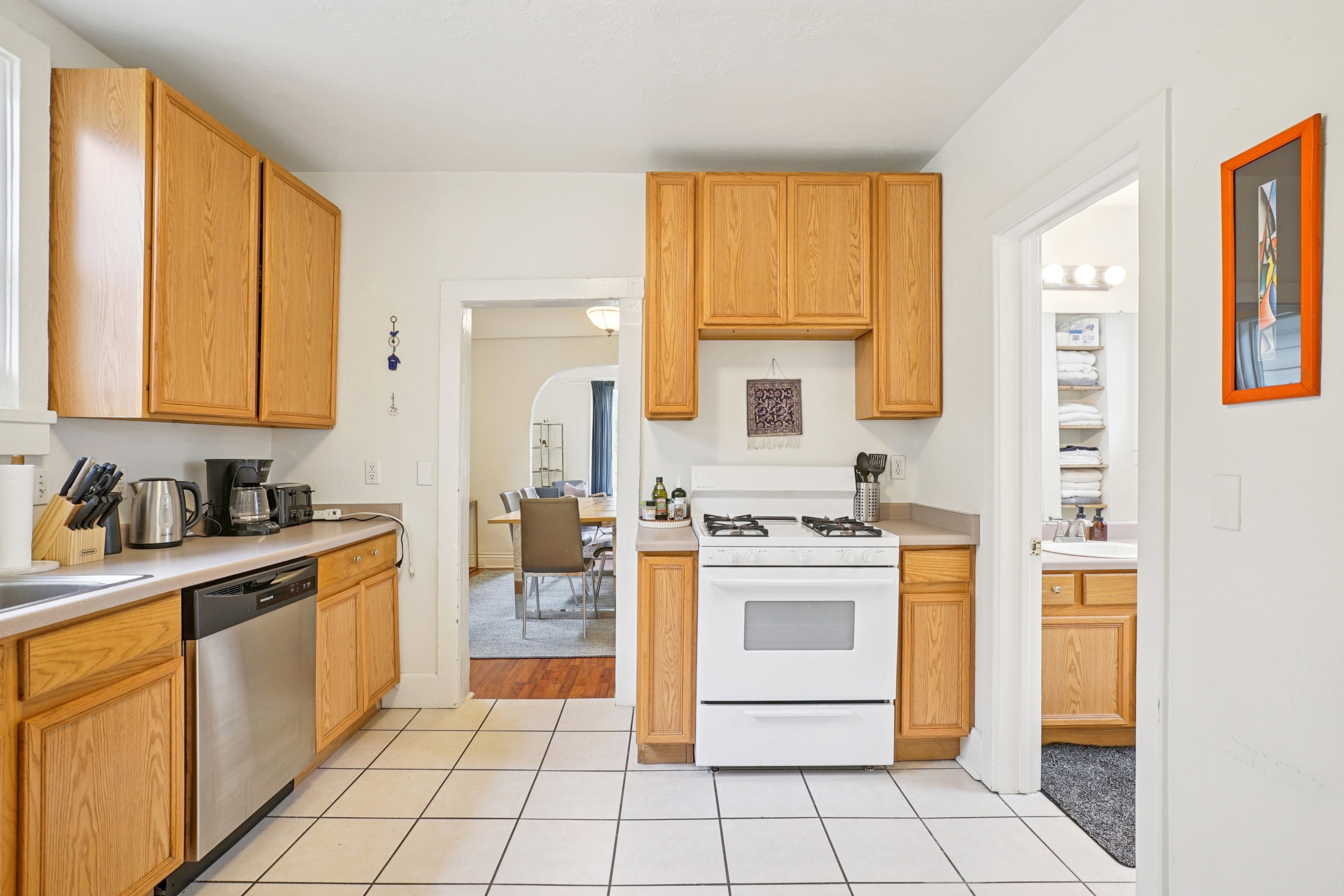 Kitchen featuring gas range gas stove, light countertops, stainless steel dishwasher, light tile patterned flooring, and arched walkways