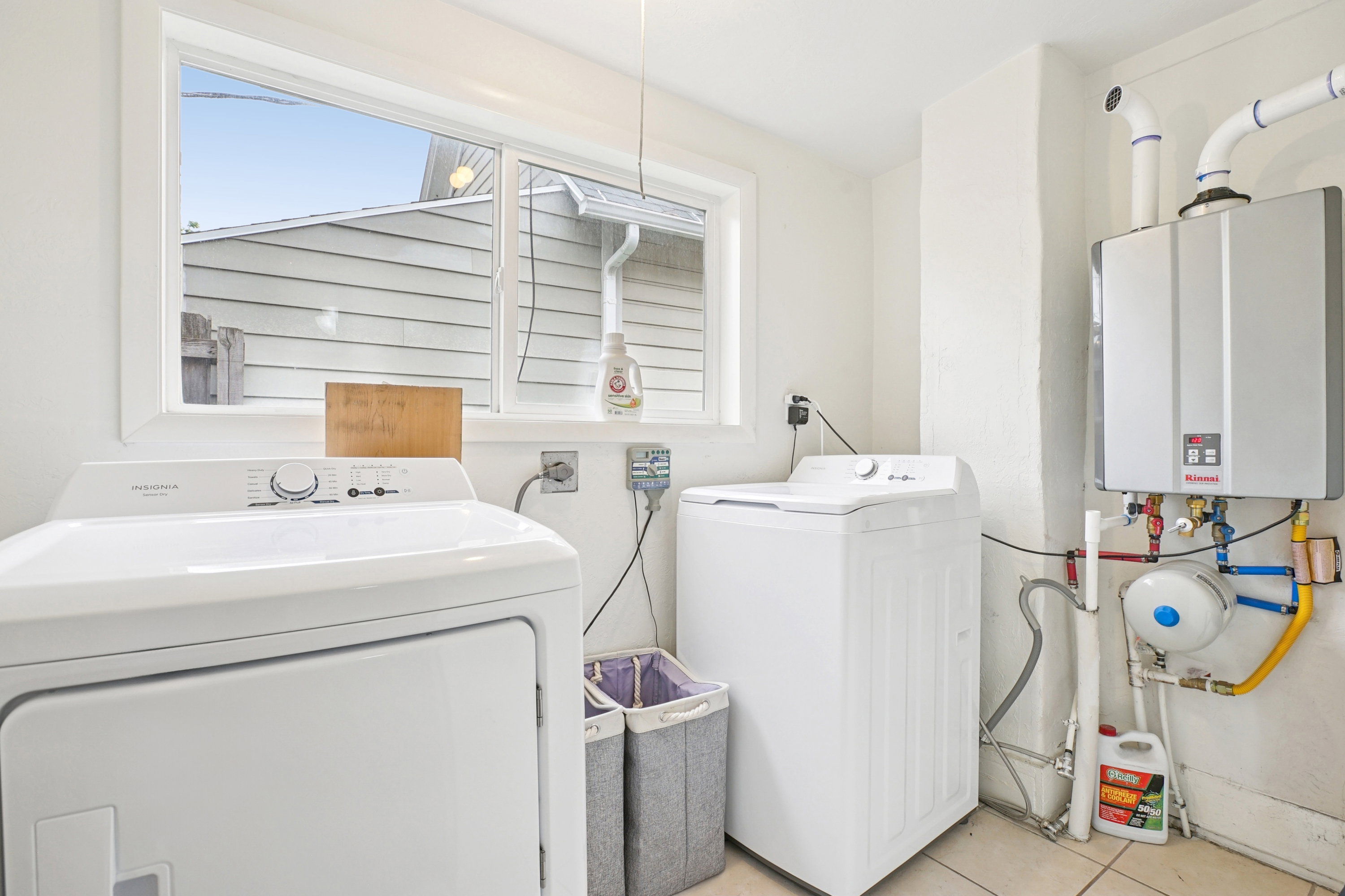 Laundry room featuring washer and dryer, tankless water heater, and light tile patterned floors
