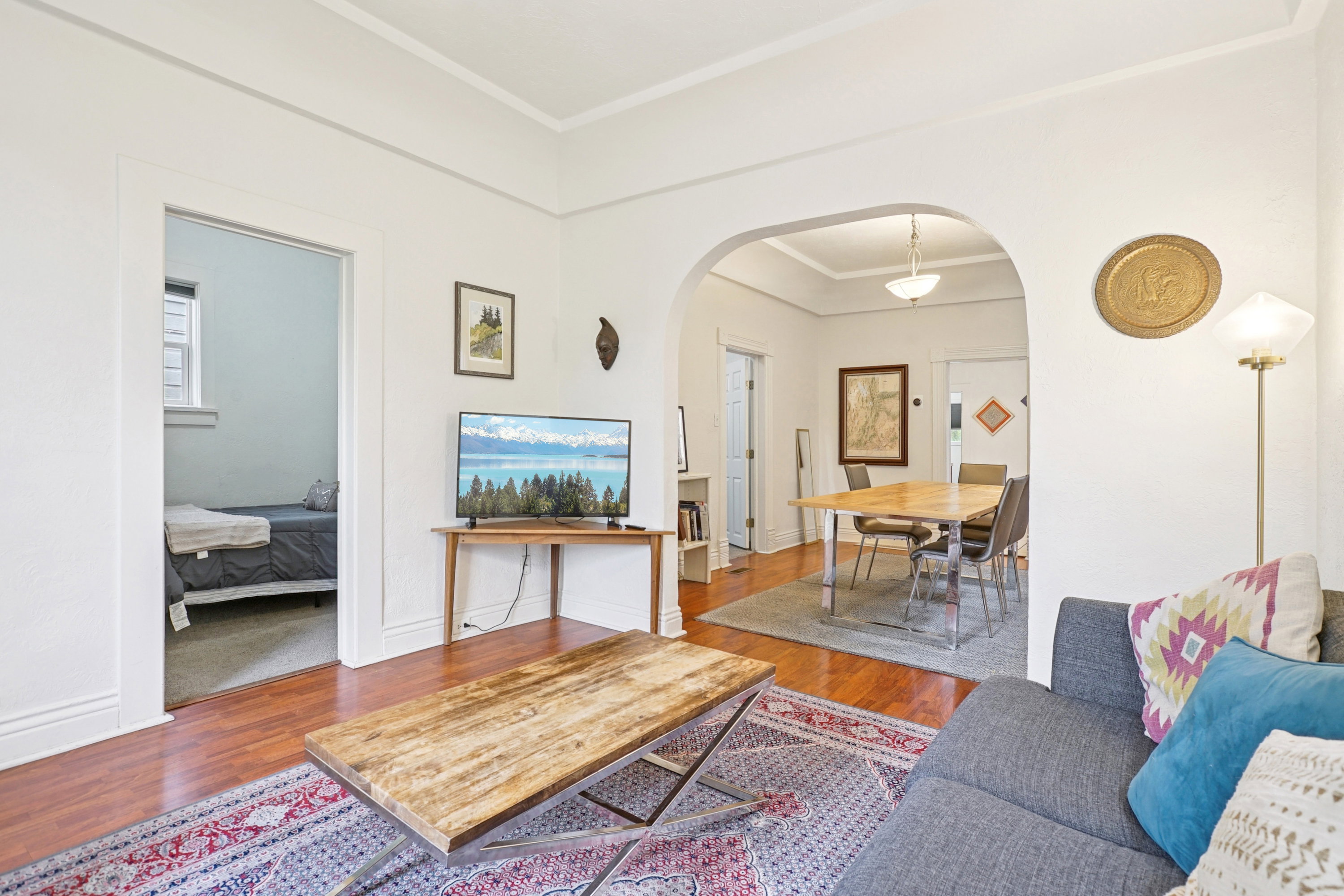 Living room featuring wood finished floors, crown molding, and arched walkways
