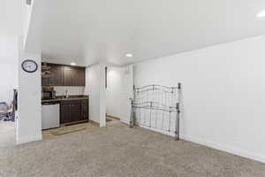 Indoor wet bar featuring dark wood finish cabinetry, light carpet, recessed lighting, black microwave, and fridge