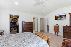 Bedroom with a spacious closet, lofted ceiling, ceiling fan, light carpet, and recessed lighting