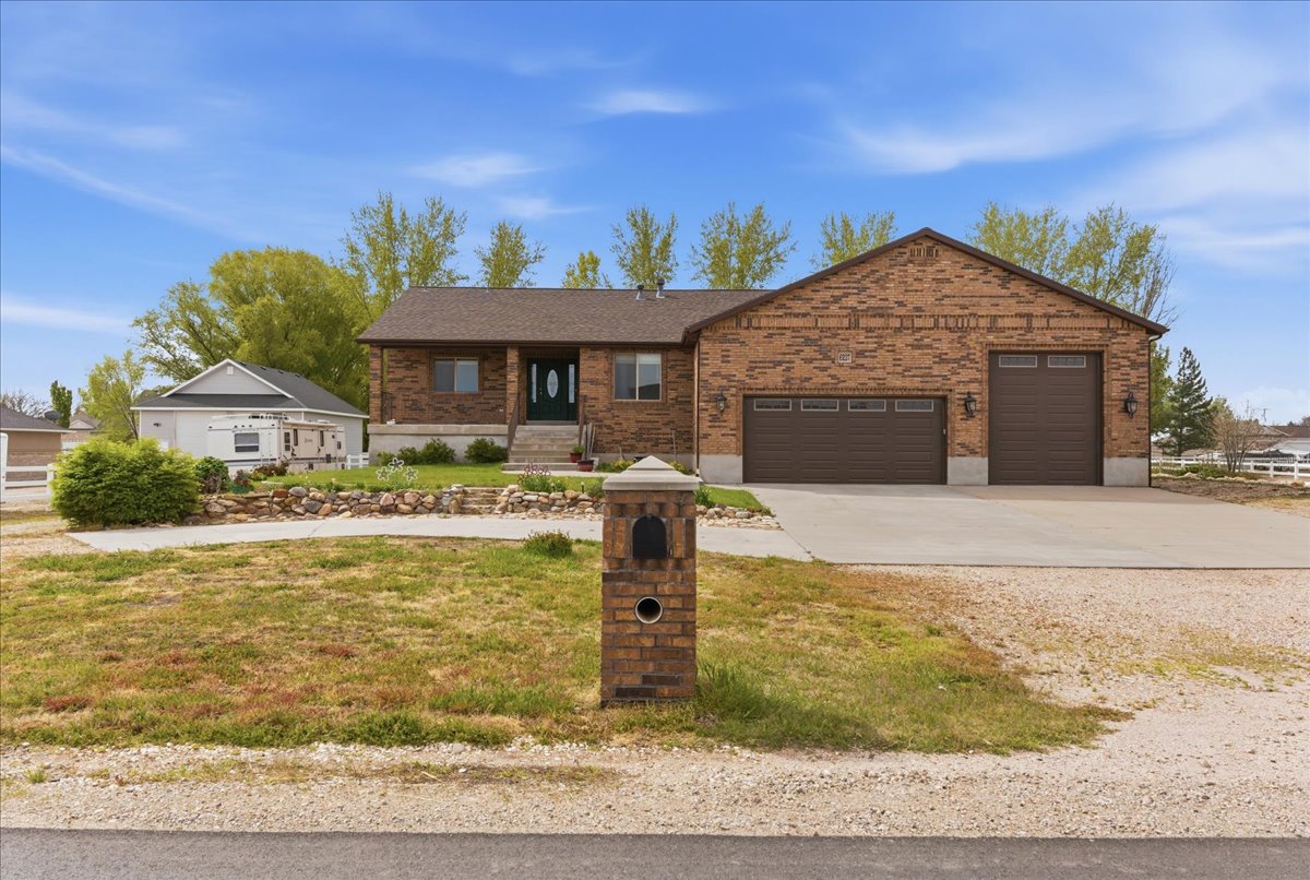 Single story home with concrete driveway, an attached garage, a front yard, brick siding, and a shingled roof