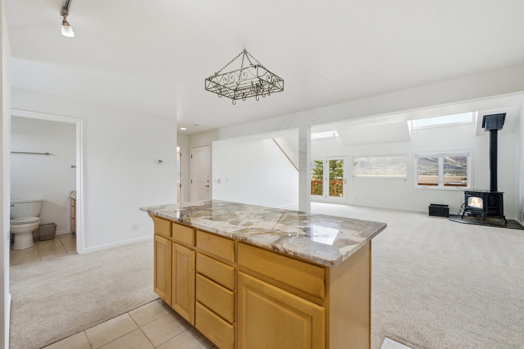 Kitchen with light carpet, a kitchen island, open floor plan, a wood stove, and light tile patterned floors