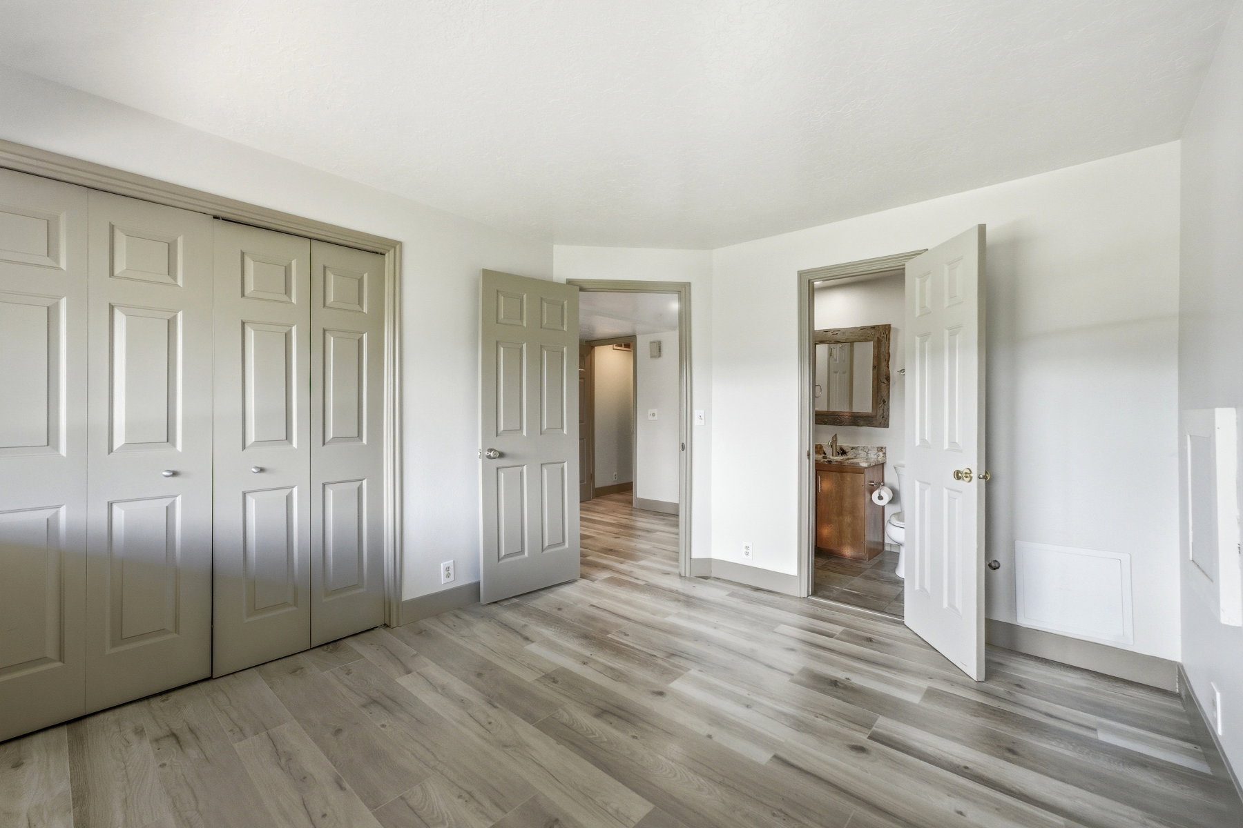Unfurnished bedroom with light wood-style floors, ensuite bathroom, and a closet