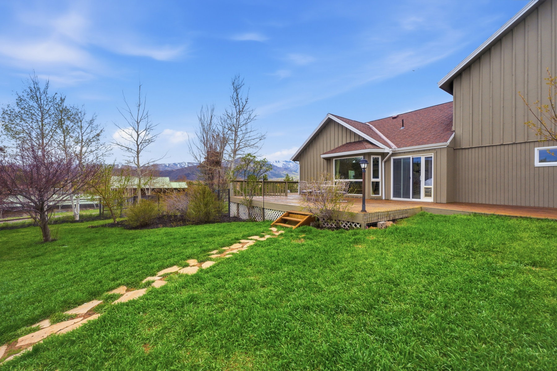 View of green lawn with a deck with mountain view