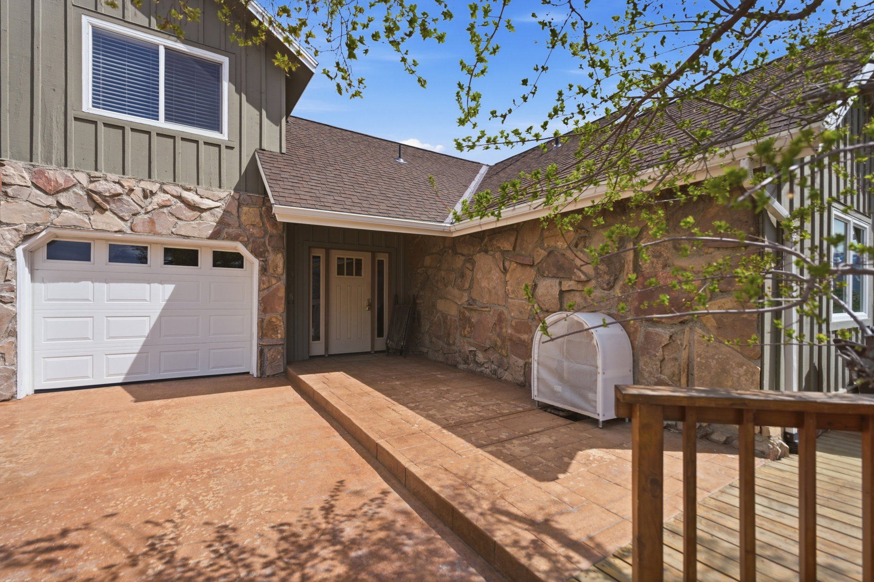 Property entrance featuring stone siding, board and batten siding, a shingled roof, and driveway