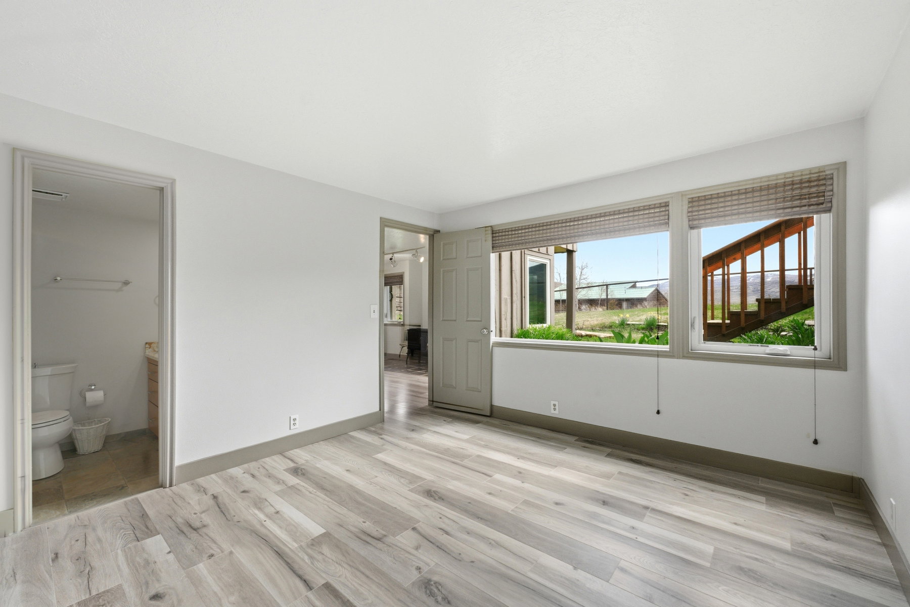 Unfurnished bedroom with light wood finished floors and connected bathroom