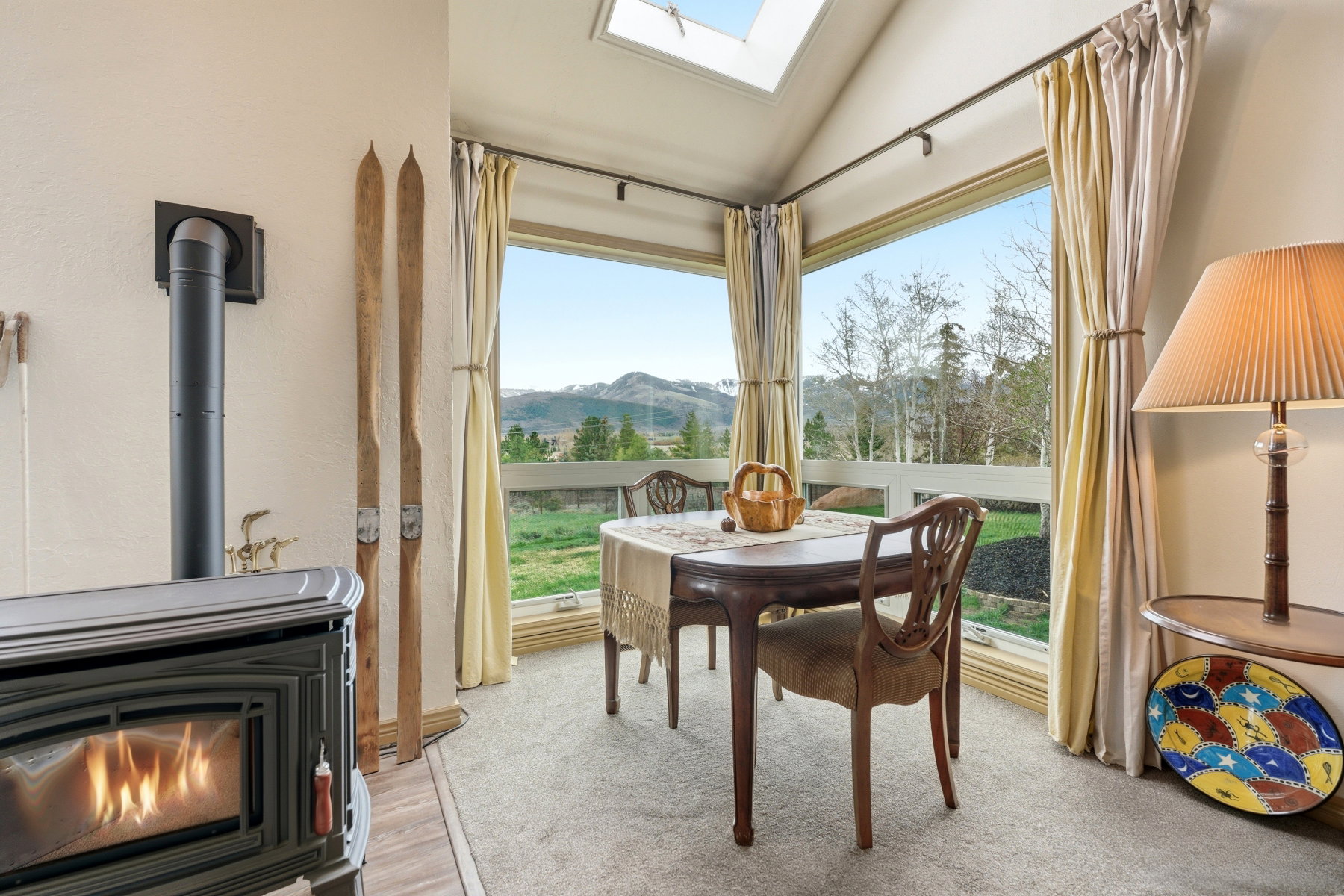 Dining room featuring a mountain view, a wood stove, a skylight, and vaulted ceiling