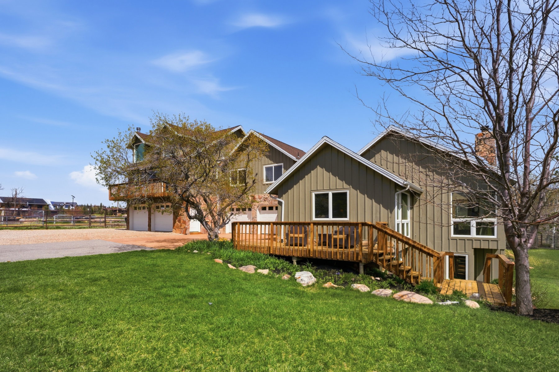 View of front of house featuring driveway, board and batten siding, a deck, a front yard, and a chimney