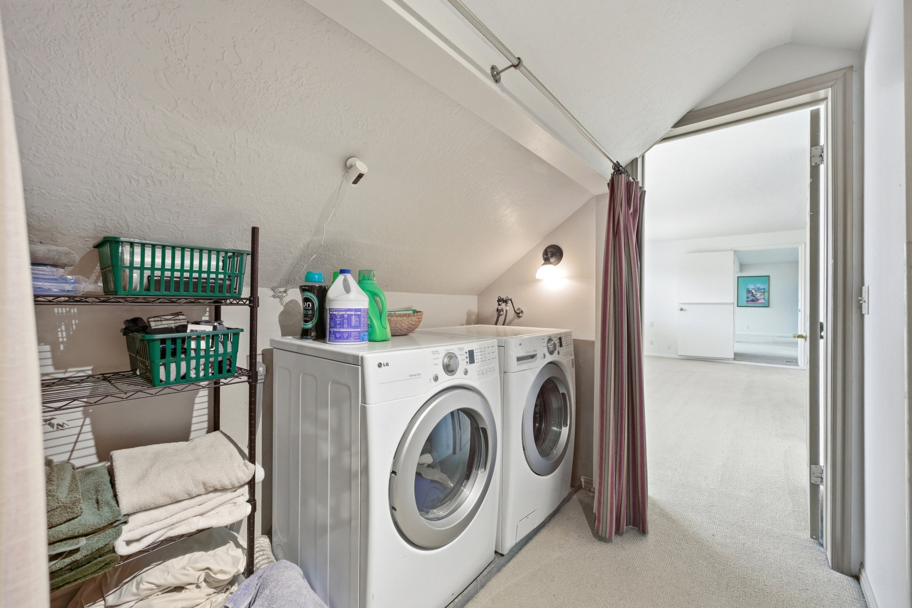 Laundry area with vaulted ceiling, light carpet, and independent washer and dryer