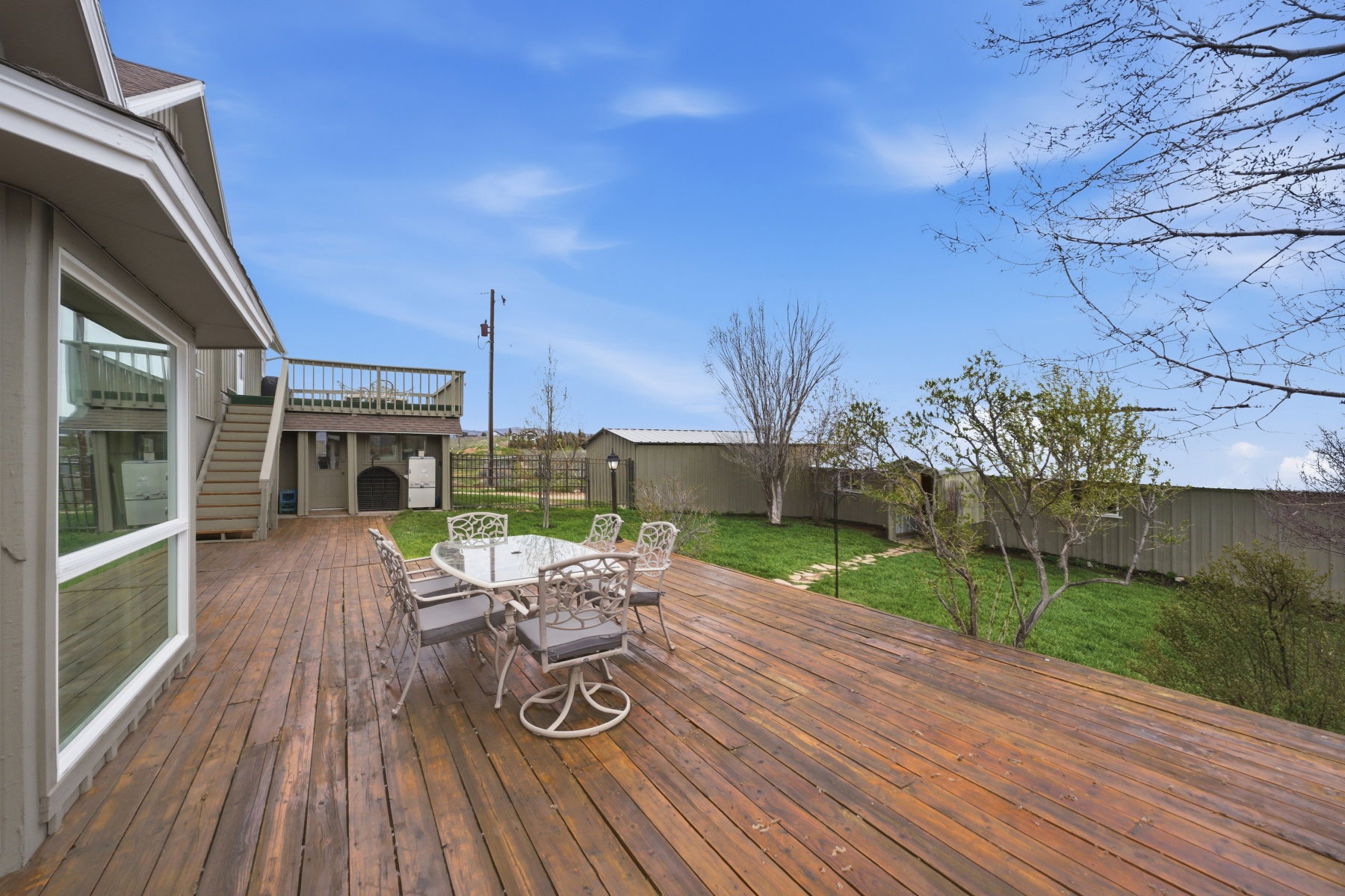 Deck with outdoor dining space, a fenced backyard, and an outdoor structure