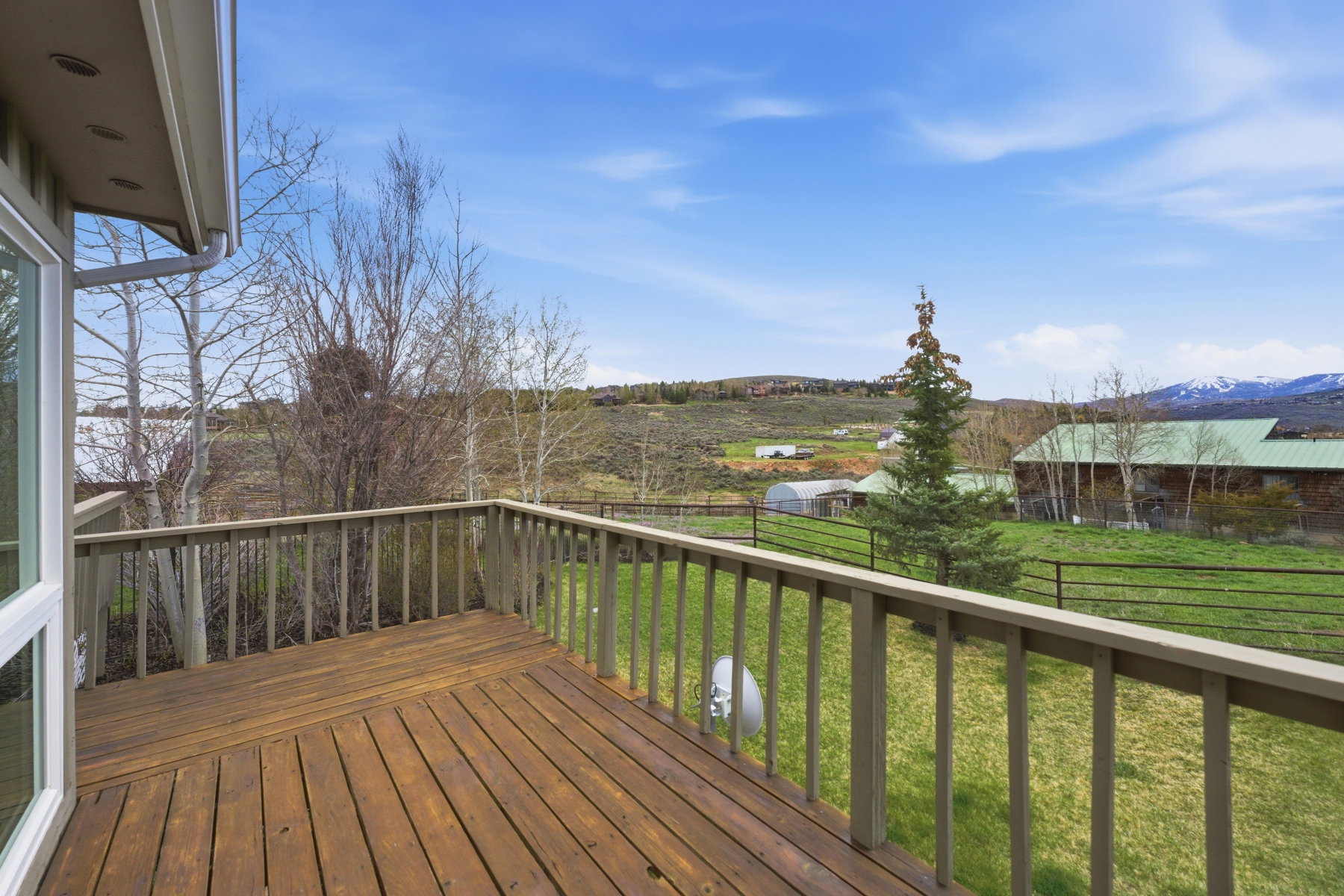 Wooden terrace with a fenced backyard, a mountain view, and a view of rural / pastoral area