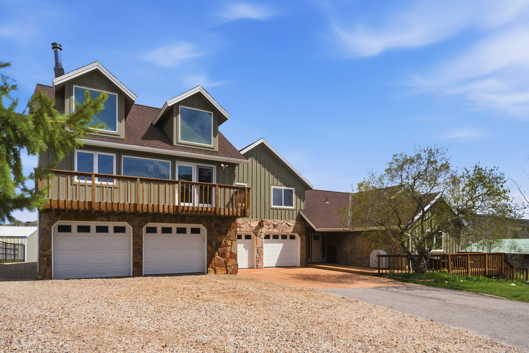 View of front facade featuring stone siding, driveway, board and batten siding, an attached garage, and roof with shingles