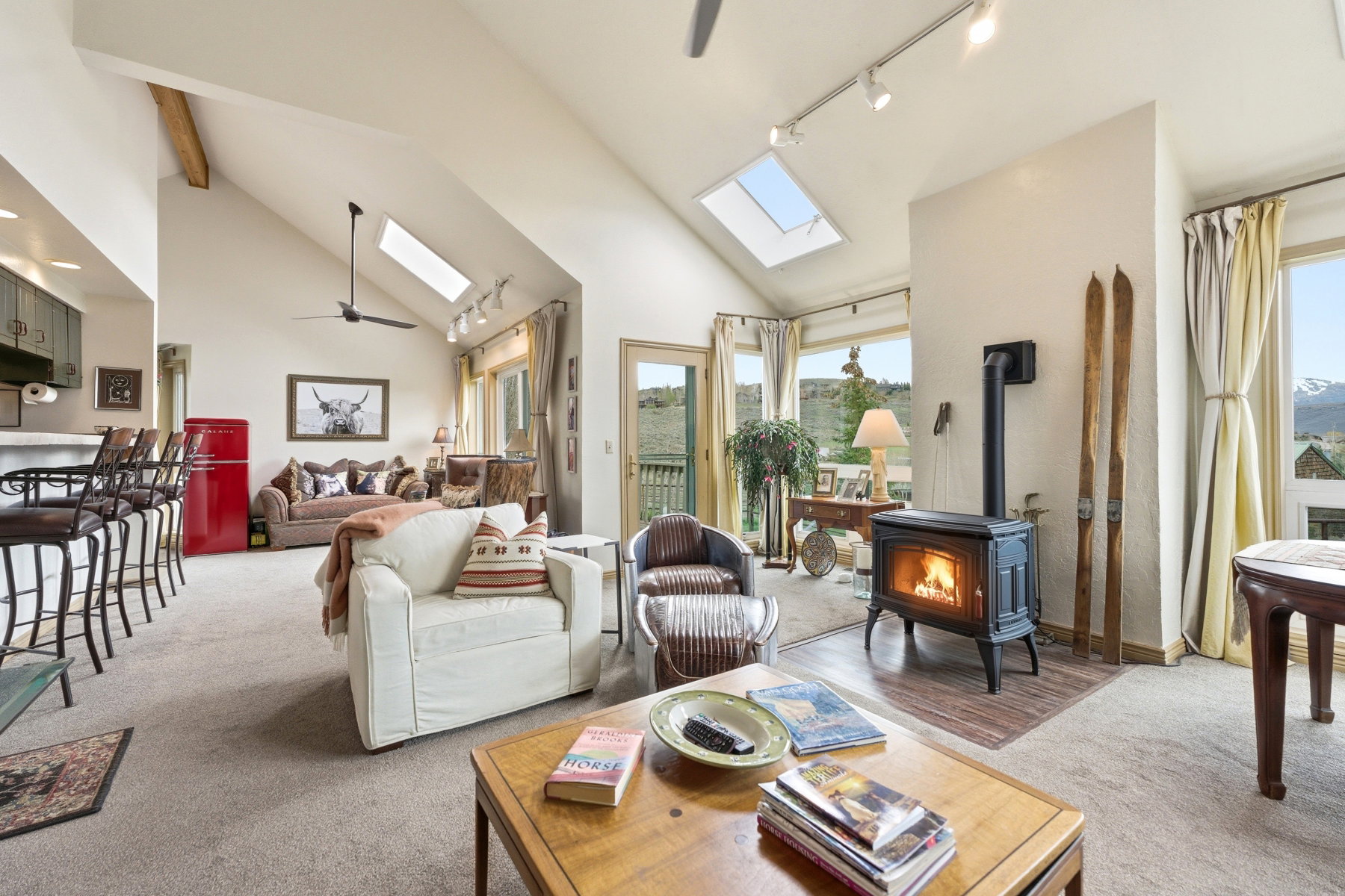 Living room with rail lighting, a skylight, light colored carpet, a ceiling fan, and vaulted ceiling