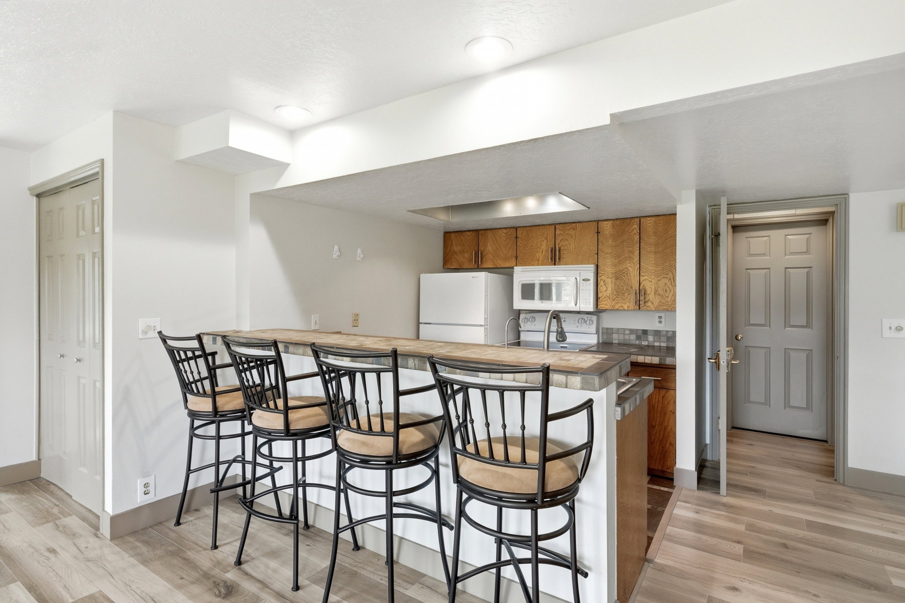 Kitchen with a kitchen breakfast bar, a peninsula, wood finish cabinetry, and white appliances