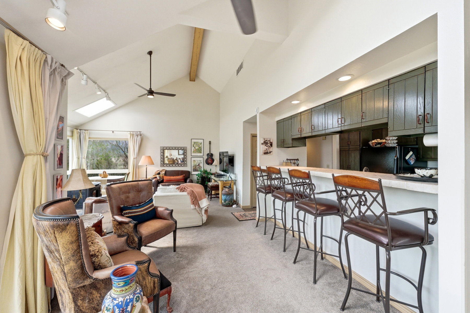 Living area with light colored carpet, rail lighting, and a ceiling fan