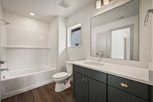 Full bath featuring vanity, bathtub / shower combination, and dark wood-type flooring