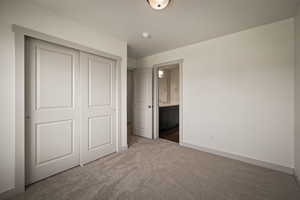 Unfurnished bedroom featuring carpet flooring, a closet, and connected bathroom