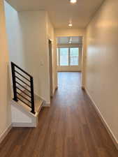 Hall with dark wood-style floors and recessed lighting.  Black metal railing.