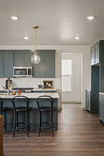 Kitchen featuring a breakfast bar, dark wood finished floors, stainless steel appliances, a textured ceiling, and hanging light fixtures