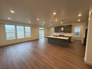 Kitchen with decorative light fixtures, open floor plan, a center island with sink, and plenty of natural light