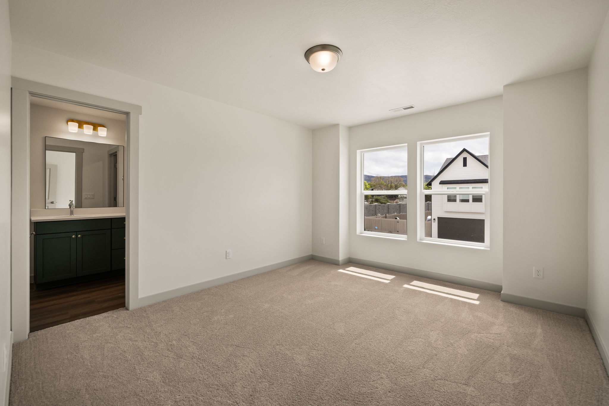 Unfurnished bedroom with dark carpet and ensuite bathroom