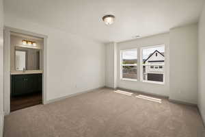 Unfurnished bedroom with dark carpet and ensuite bathroom