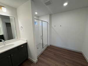 Primary bathroom with vanity, a shower stall, and dark wood finished floors