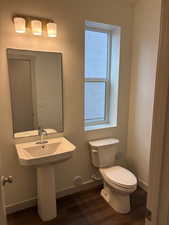 Half bath with toilet and dark wood finished floors