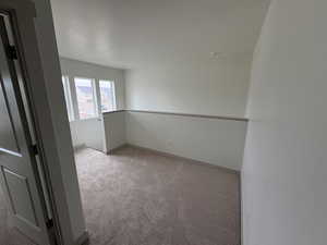 Unfurnished loft area featuring light carpet and baseboards