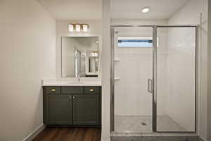 Bathroom featuring vanity, dark wood-type flooring, a shower stall, and a textured ceiling