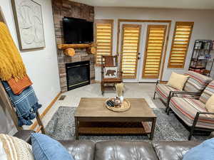Carpeted living room featuring a fireplace and baseboards