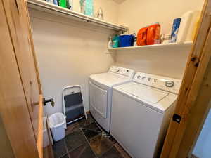 Laundry area with dark stone finish floors and washing machine and dryer