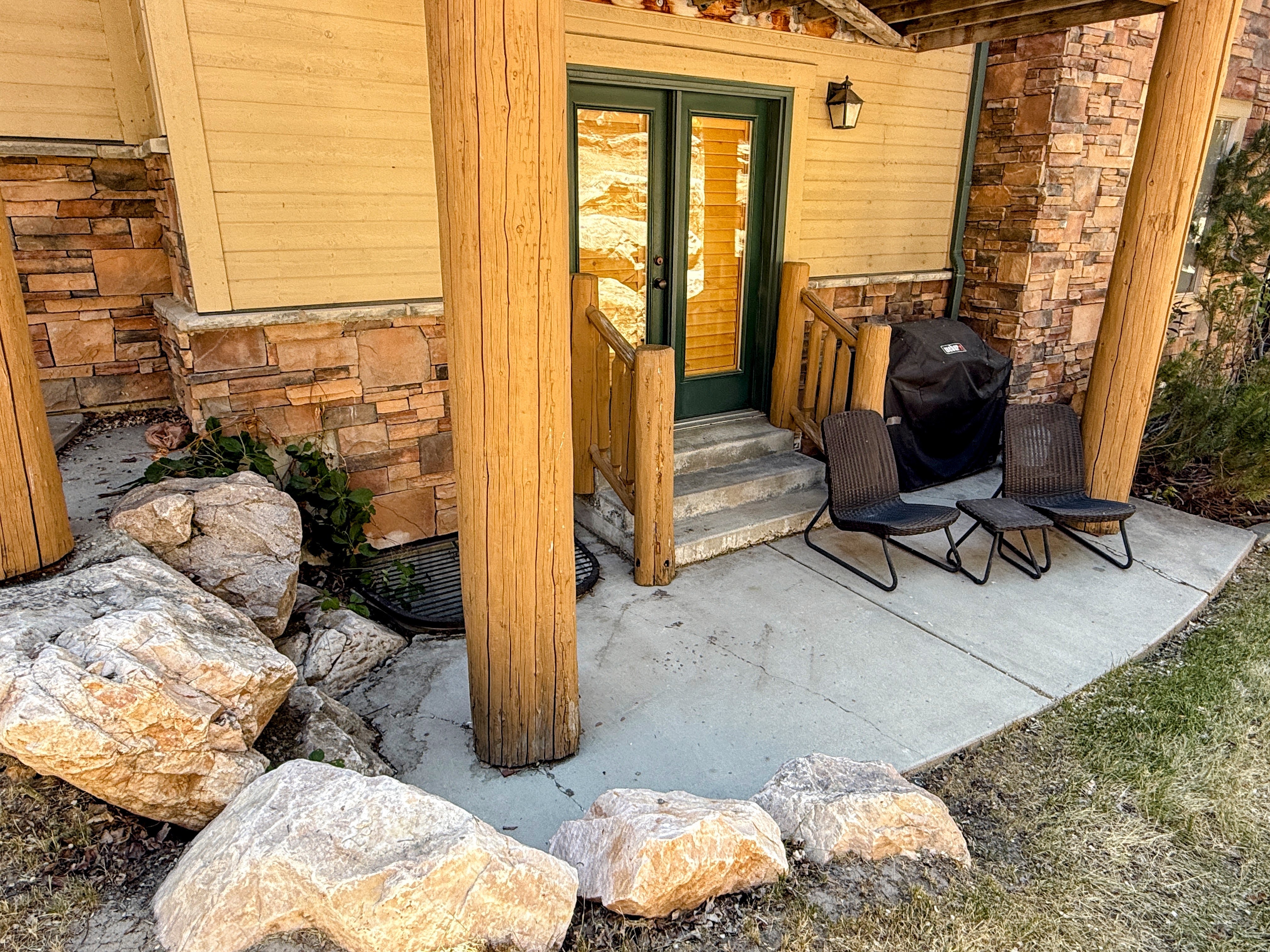 Entrance to property featuring stone siding and a patio